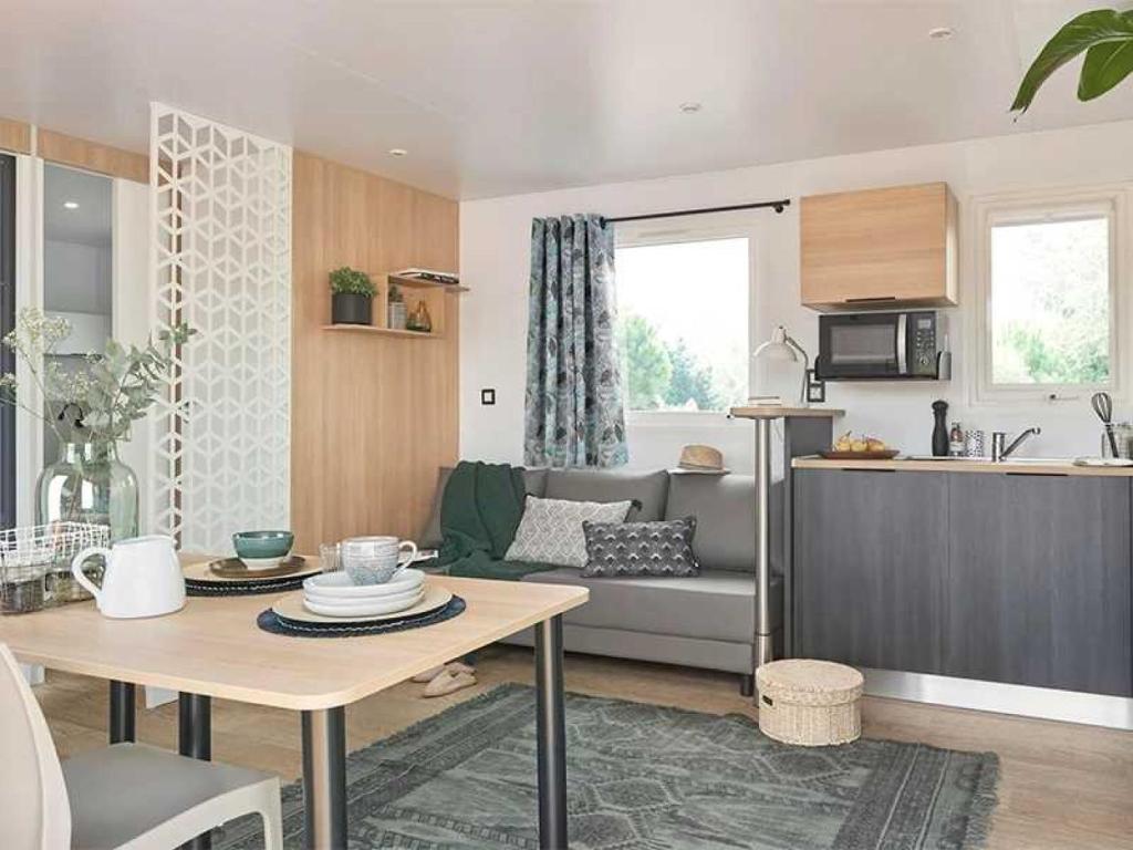 Il dispose d'une cuisine et d'un salon avec un canapé et une table. dans l'établissement Camping 3 étoiles - Parc aquatique - eecehf, à Fréjus