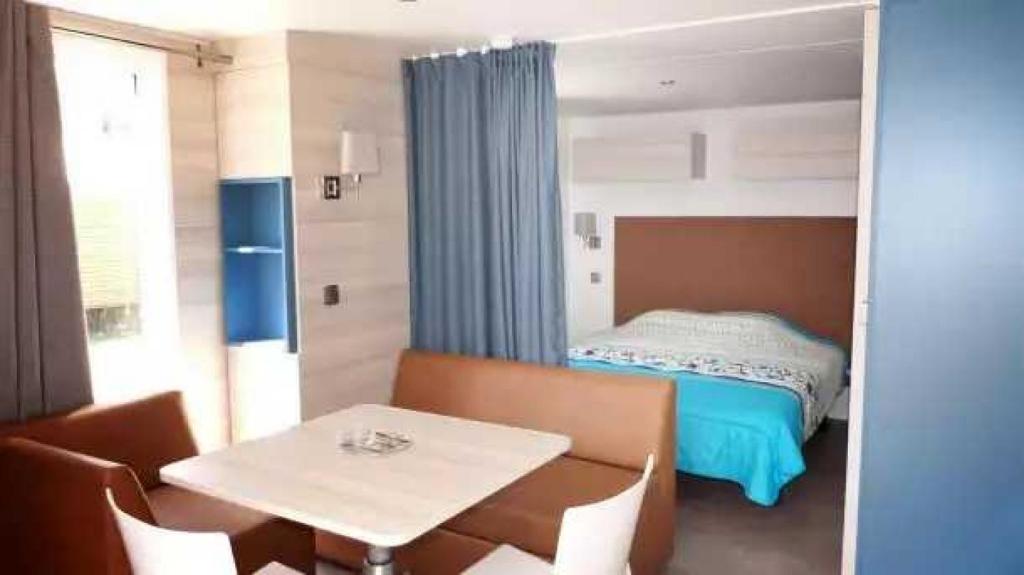 une chambre avec un lit, une table et des chaises dans l'établissement Camping 4 étoiles - Parc aquatique - eece0c, à Grimaud