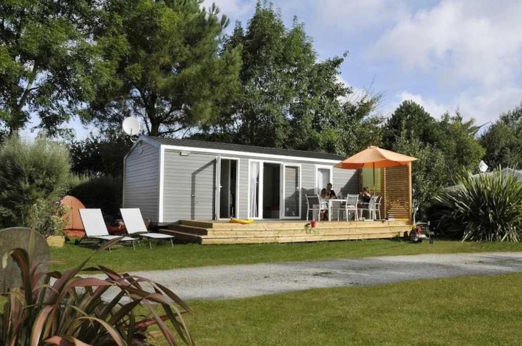 une petite maison avec une véranda et un parasol dans l'établissement Camping 3 étoiles - efdbeb, à Plobannalec-Lesconil