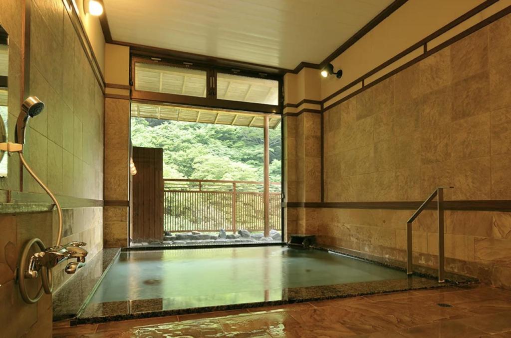 - une piscine dans une chambre dotée d'une grande fenêtre dans l'établissement Shima Onsen Yoshimoto, à Nakanojo