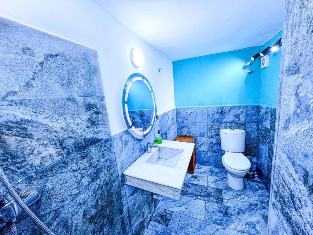 La salle de bains bleue est pourvue de toilettes et d'un miroir. dans l'établissement Riad Verus, à Fès