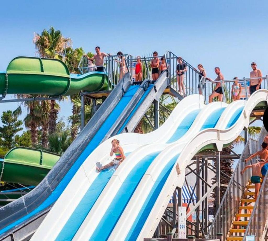 un groupe de personnes utilisant un toboggan aquatique dans un parc aquatique dans l'établissement Mobil-home 3 chambres, Plage & piscine, camping 4 étoiles, à Torreilles