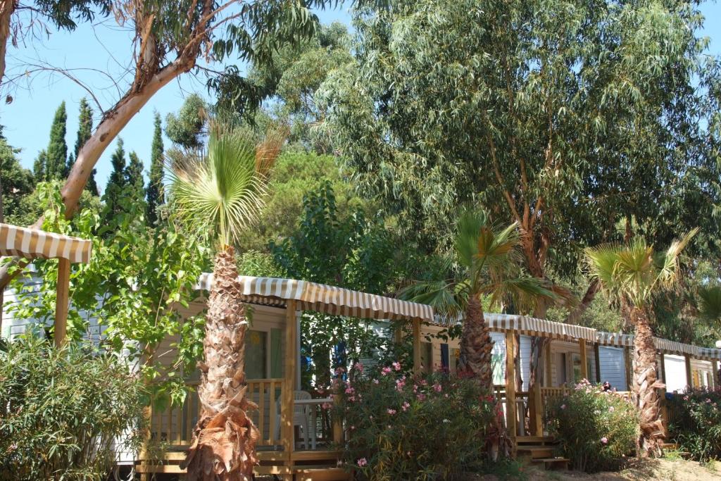 une cabane dans les bois avec des arbres et des fleurs dans l'établissement Camping de la Baie, à Cavalaire-sur-Mer