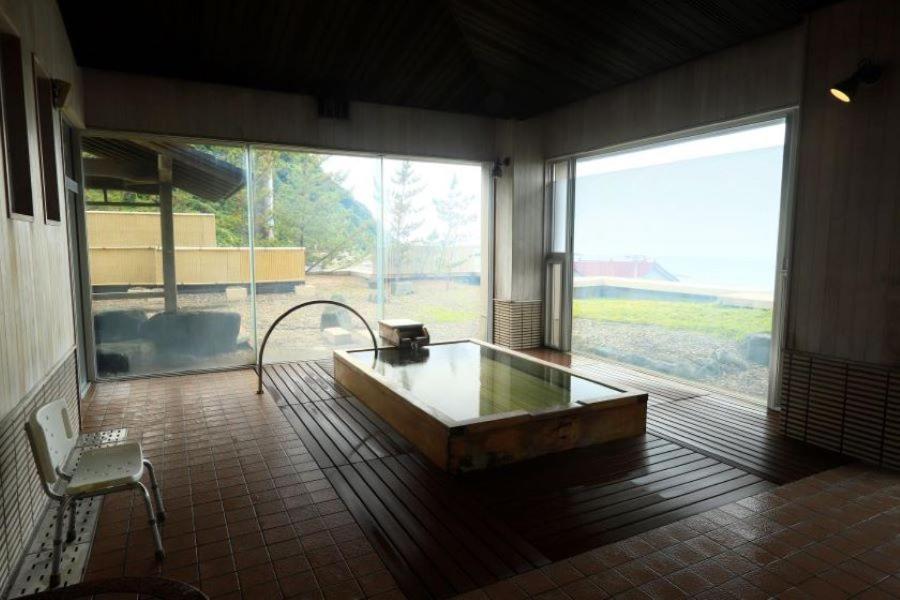 - une grande salle de bains pourvue d'une baignoire et d'une grande fenêtre dans l'établissement Kameya Hotel, à Tsuruoka