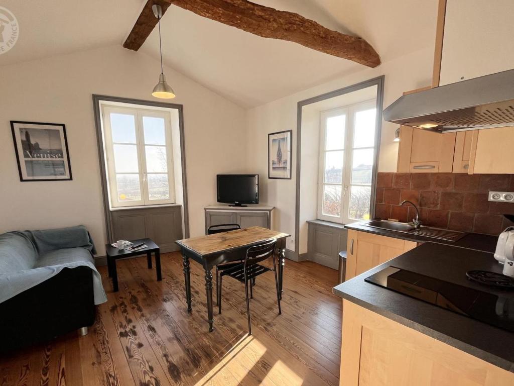 une cuisine et un salon avec une table et un canapé dans l'établissement Gîte charmant avec piscine, jardin, et produits fermiers à Saint-André-d'Apchon - FR-1-496-142, à Saint-André-dʼApchon