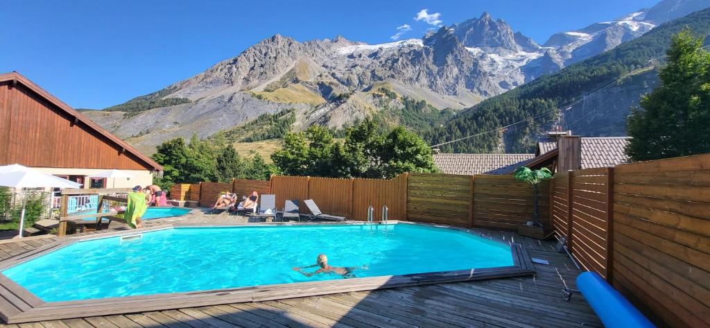 une personne dans une piscine avec des montagnes en arrière-plan dans l'établissement Locations Cosy - Village Piéton avec Vue Glaciers - chez Philippe, à La Grave