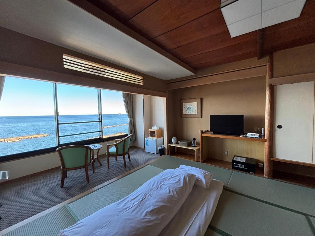 une chambre avec un lit et une vue sur l'océan dans l'établissement Kameya Rakan, à Itō