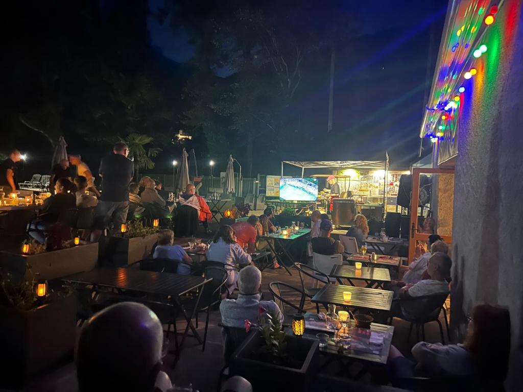 Une foule de personnes assises à des tables la nuit dans l'établissement Camping du Valentin, à Laruns
