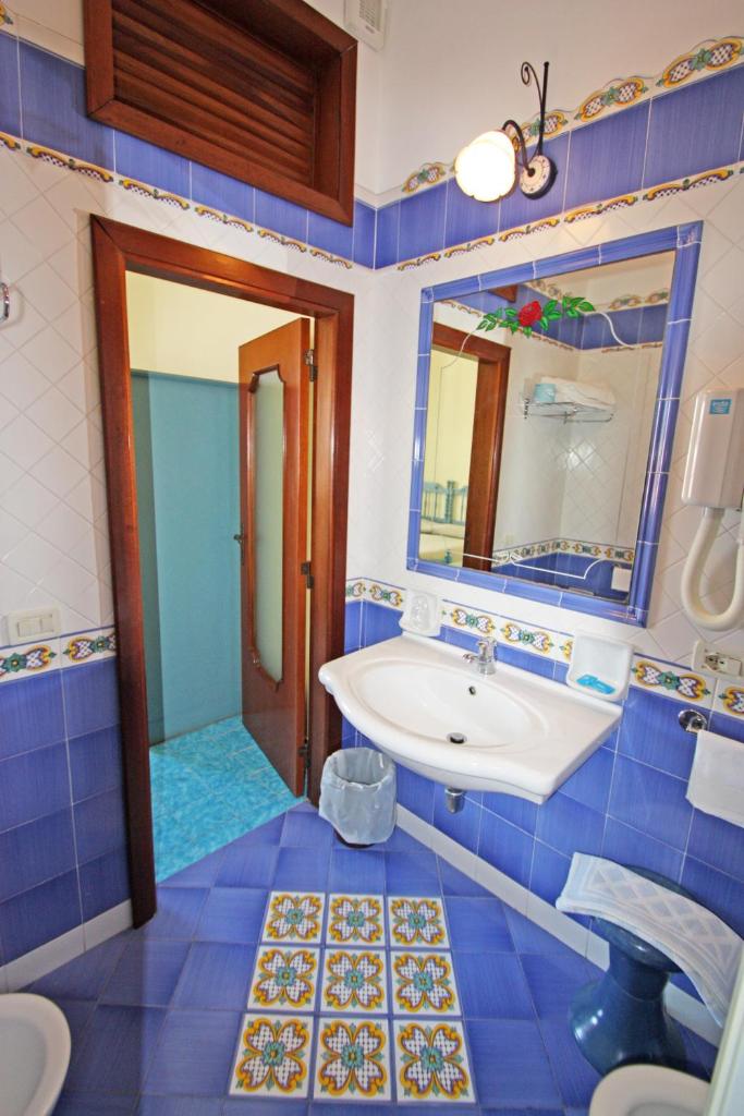 une salle de bain bleue avec un lavabo et un miroir dans l'établissement Hotel La Certosa, à Massa Lubrense