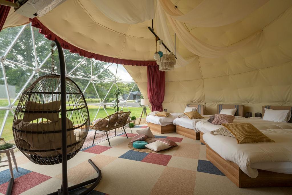 - une chambre avec 2 lits et une balançoire dans une tente dans l'établissement グランピングヴィレッジ富士河口湖, à Narusawa