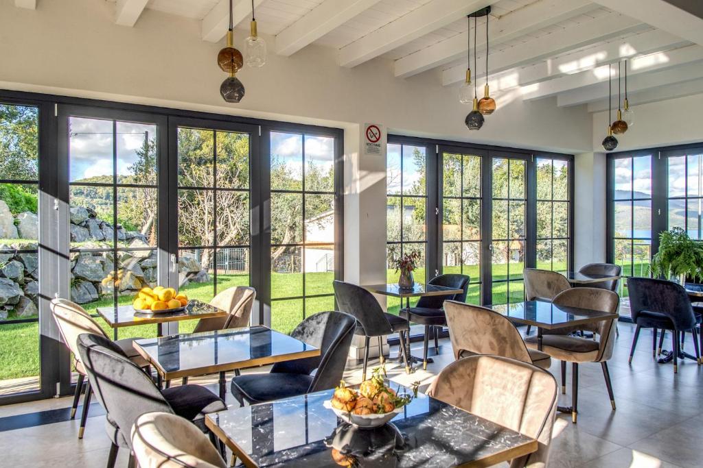 un restaurant avec des tables et des chaises et de grandes fenêtres dans l'établissement Vigna Caio Relais & Spa, à Bracciano