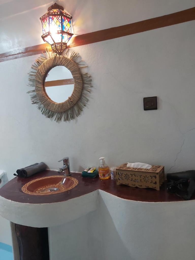 une salle de bain avec un lavabo et un miroir au mur dans l'établissement DAR DANI café restaurant, à Boumalne