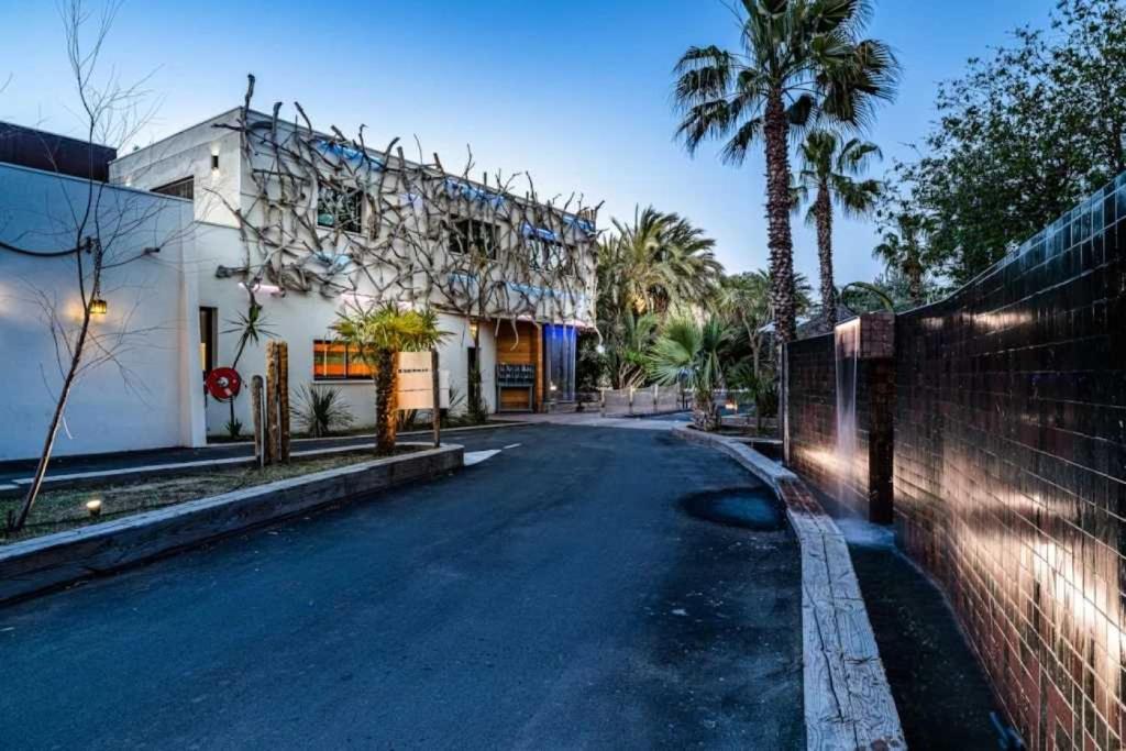 une rue vide en face d'un bâtiment planté de palmiers dans l'établissement Camping 4 étoiles - Parc aquatique - ccaffga, au Cap d'Agde