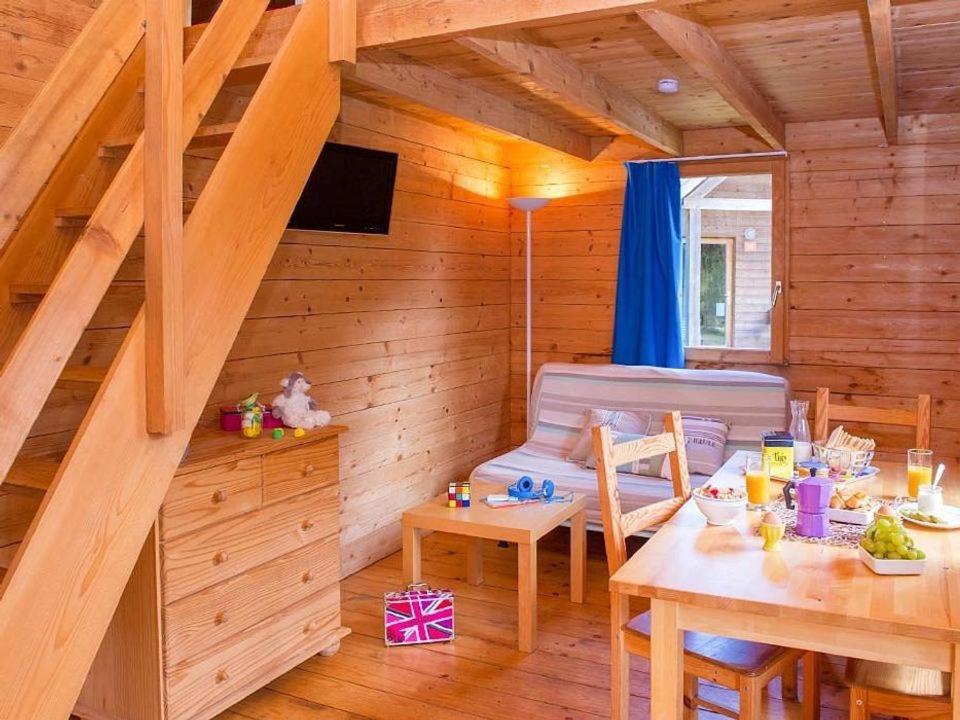 une chambre avec une table et un canapé dans une cabine dans l'établissement Camping Rieumontagné, à Nages 3 autres photos