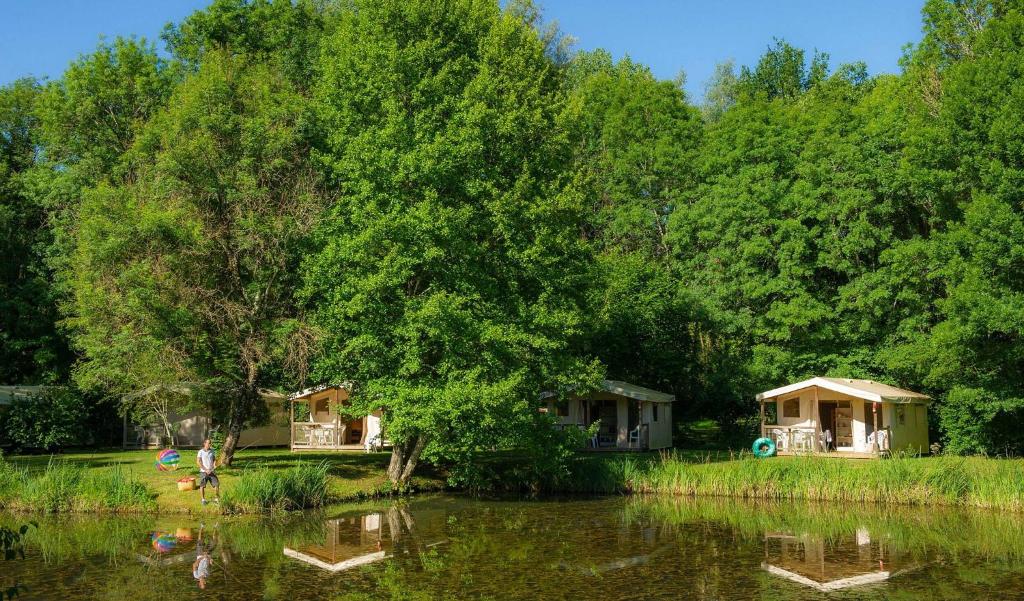 - un groupe de cottages à côté d'une rivière arborée dans l'établissement Camping Aqua Viva, à Carsac-Aillac 2 autres photos