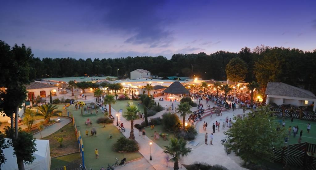 un groupe de personnes se promenant autour d'un parc la nuit dans l'établissement Happy Camp Mobile Homes in Camping Le Domaine La Yole, à Vendres