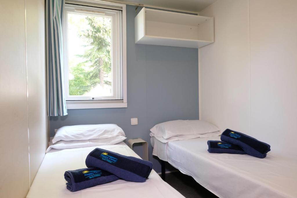 deux lits jumeaux dans une chambre avec fenêtre dans l'établissement Happy Camp Mobile Homes in Camping Le Domaine La Yole, à Vendres