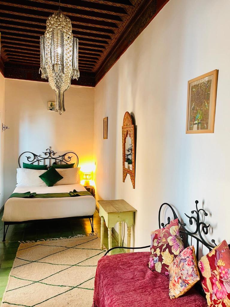une chambre avec un lit et un lustre dans l'établissement Riad Zarka By La Siredrah, à Marrakech
