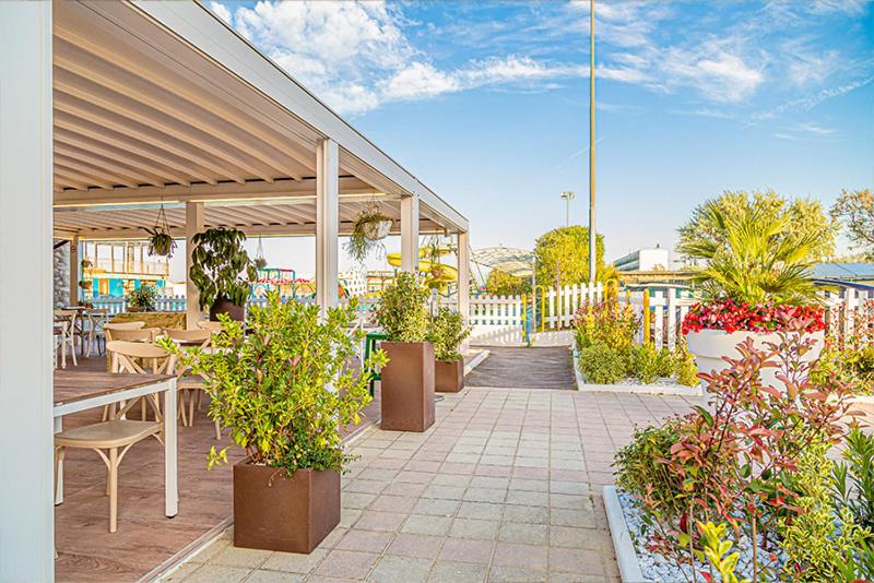 un patio avec des tables, des chaises et des plantes en pot dans l'établissement Hotel Sirena - B&B, à Cesenatico