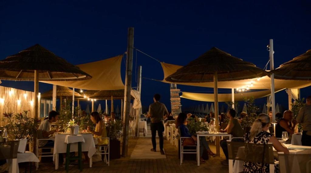 un groupe de personnes assises à des tables sous des parasols la nuit dans l'établissement Hotel Sirena - B&B, à Cesenatico