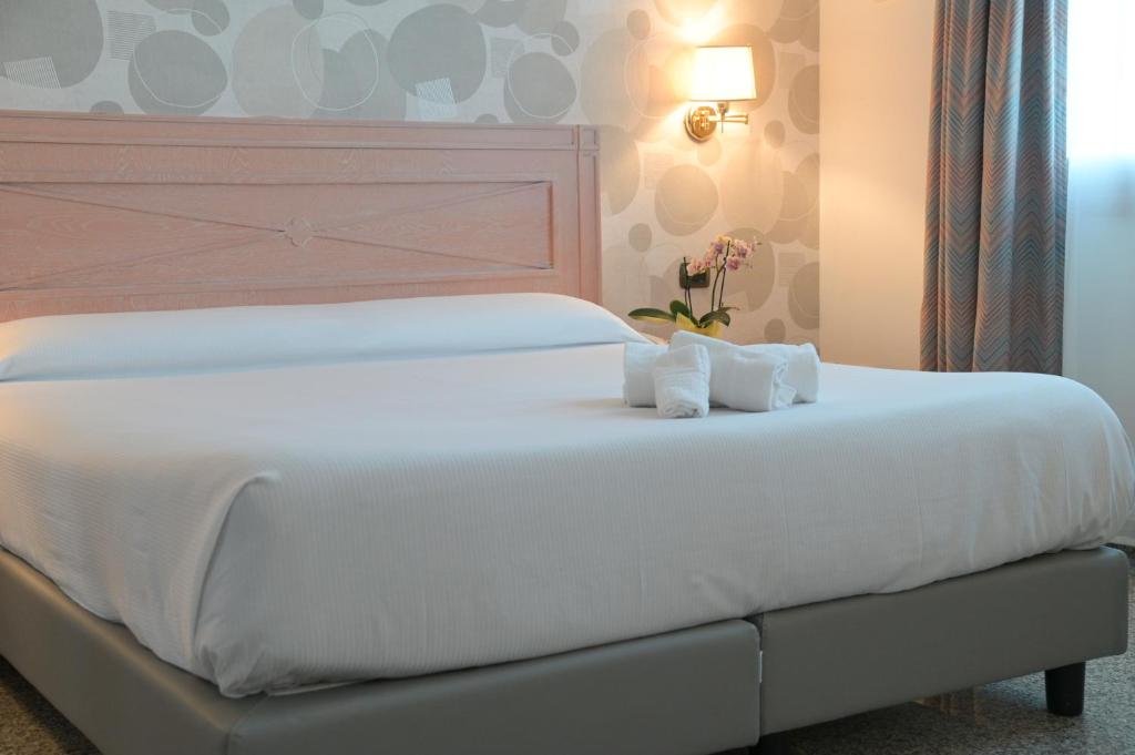 - un grand lit blanc avec 2 serviettes dans l'établissement Residence Hotel L'incanto Di Boccadarno, à Marina di Pisa