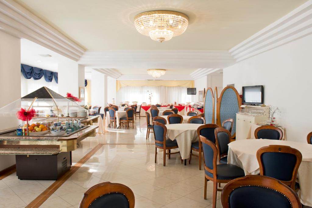 une salle à manger avec tables et chaises et un lustre dans l'établissement Hotel City, à Montesilvano