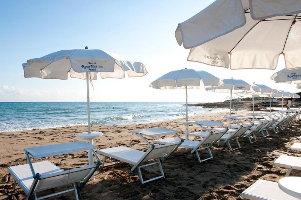 une rangée de chaises et de parasols sur une plage dans l'établissement Luxury Ostuni Beachfront Villa with Pool & Private Parking, à Ostuni