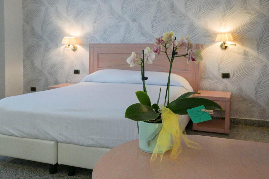 - une chambre avec un lit et un vase avec des fleurs sur une table dans l'établissement Residence Hotel L'incanto Di Boccadarno, à Marina di Pisa