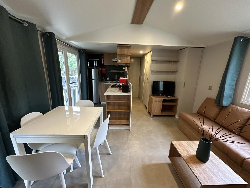 une cuisine et un salon avec une table et des chaises dans l'établissement Natuara - L'écrin du Ferret, à Lège-Cap-Ferret