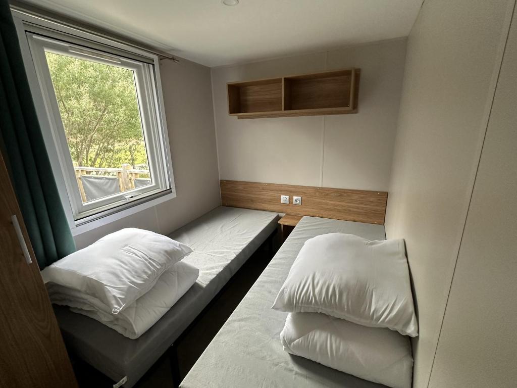 une petite chambre avec deux lits et une fenêtre dans l'établissement Natuara - L'écrin du Ferret, à Lège-Cap-Ferret