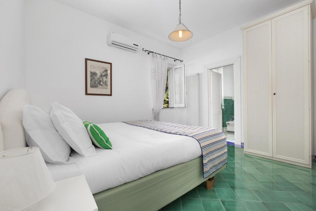 - une chambre blanche avec un lit et un sol vert dans l'établissement YourHome - Villa Claudette private pool sea view, à Massa Lubrense