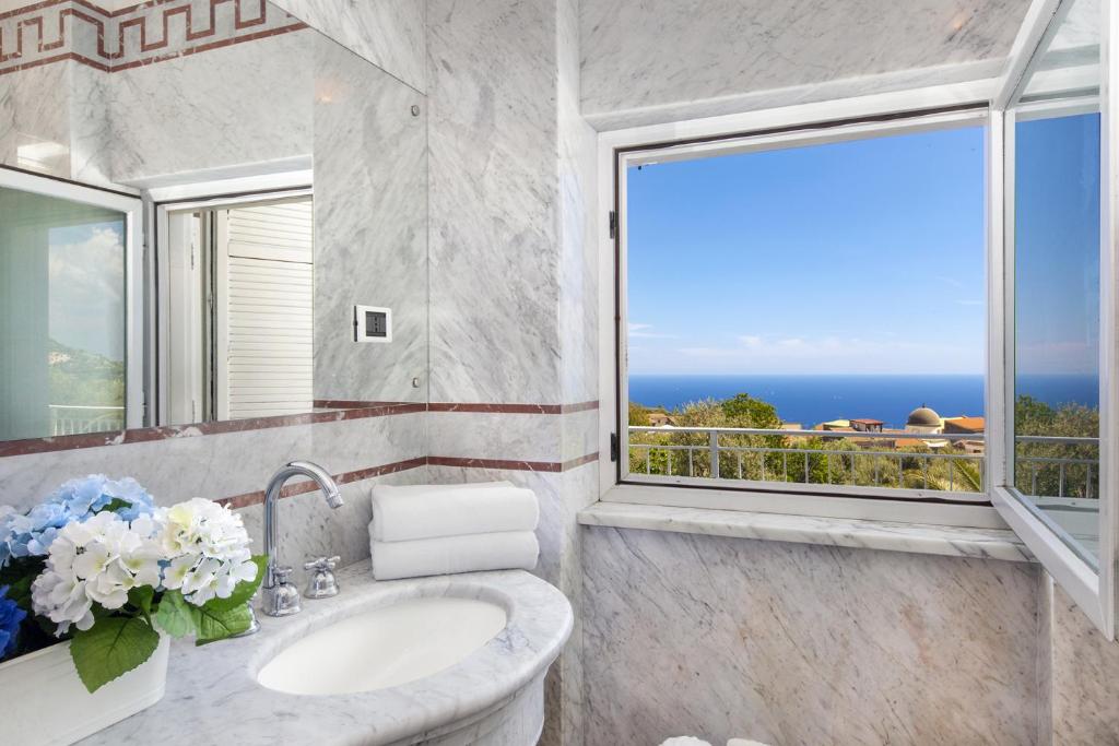 une salle de bain avec un lavabo et une grande fenêtre dans l'établissement YourHome - Villa Claudette private pool sea view, à Massa Lubrense