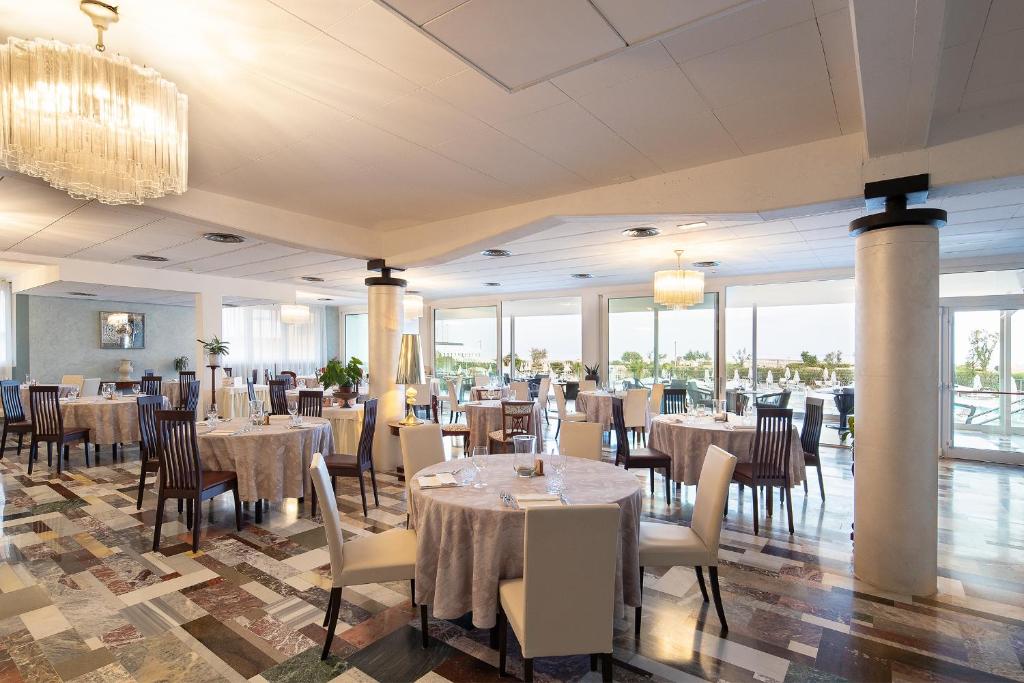 une salle à manger avec tables et chaises et un lustre dans l'établissement Fantinello Hotel, à Caorle 67 autres photos