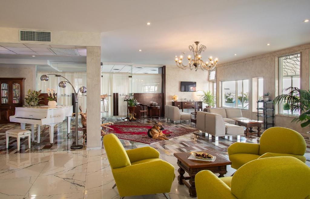 - un salon avec des chaises jaunes et un piano dans l'établissement Fantinello Hotel, à Caorle