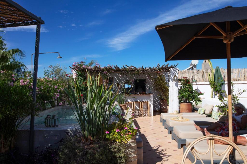 un patio avec une table, des chaises et un parasol dans l'établissement Dar Titrit, à Marrakech