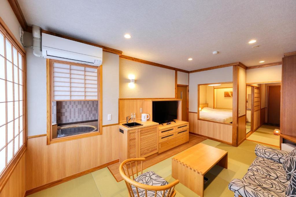 un salon avec une télévision et une chambre dans l'établissement Miyama Ouan Kyoritsu Resort, à Takayama
