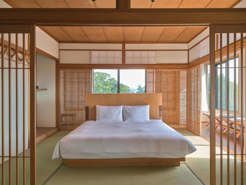 une chambre avec un lit et une grande fenêtre dans l'établissement Ohana, à Yanagawa