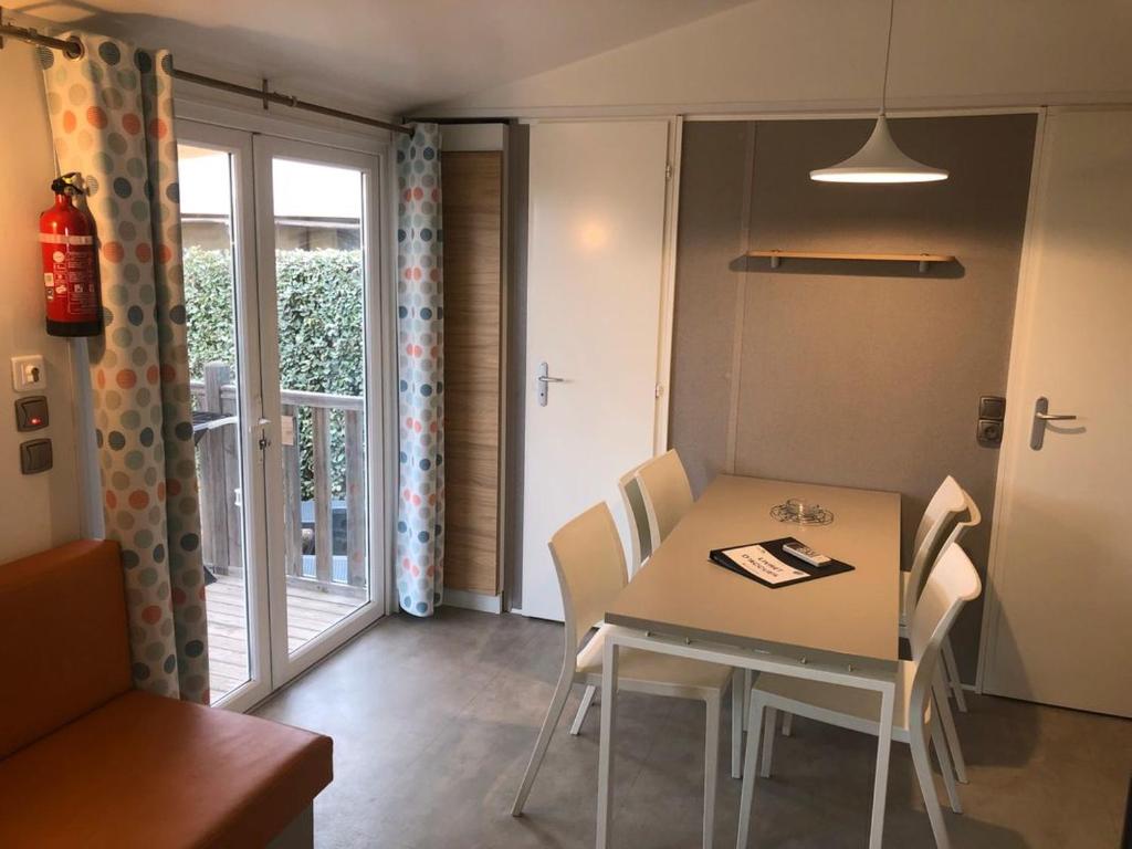 une salle à manger avec une table et des chaises et une fenêtre dans l'établissement Mobil Home Premium 6 personnes, à Torreilles