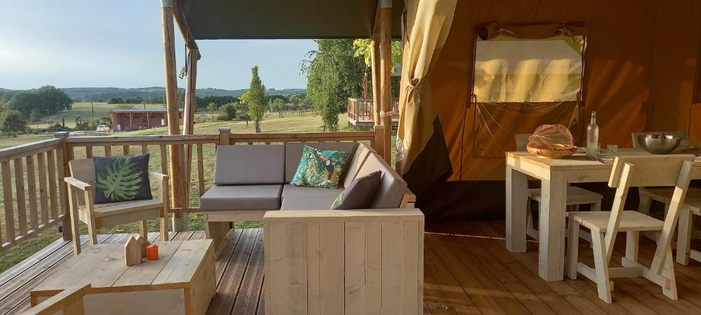 - une terrasse couverte dans une tente avec un canapé et une table dans l'établissement SAFARI LODGE MONPAZIER en pleine nature, à Saint-Cassien