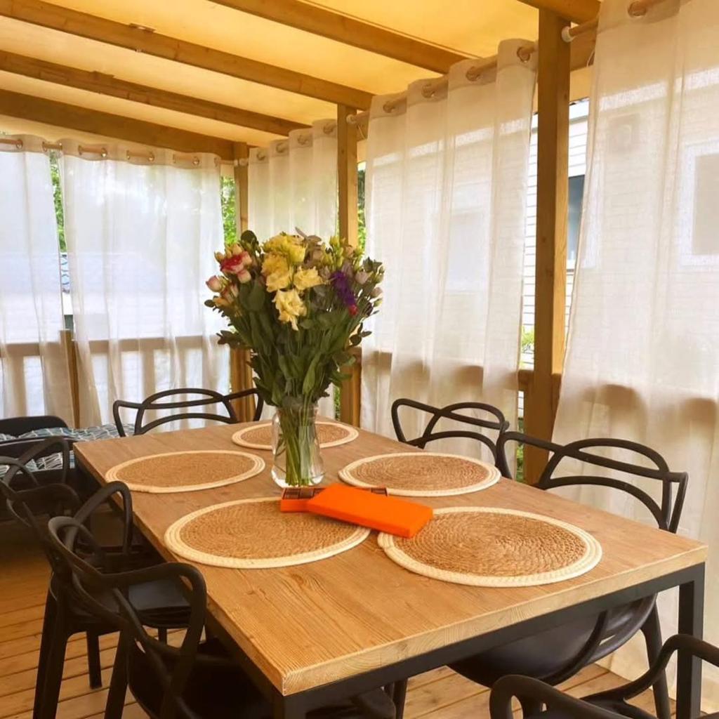 une table en bois avec un vase de fleurs dessus dans l'établissement CAP FERRET L'escale Mobil-home 6 à 8 personnes, à Lège-Cap-Ferret