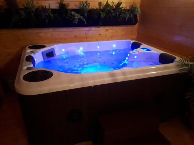 - une grande baignoire bleue dans une pièce ornée de plantes dans l'établissement Chalet flottant sur lac et spa, à Mios 1 autre photo