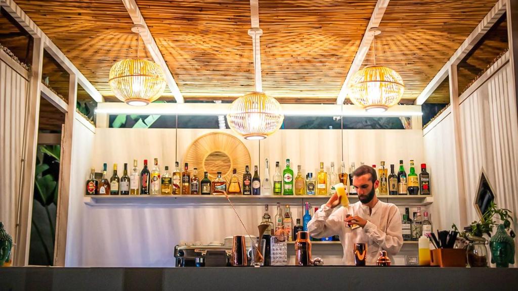un homme debout derrière un bar avec un verre dans l'établissement Borgo di Riaci Beach Resort, à Santa Domenica