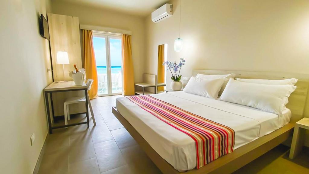 une chambre avec un grand lit avec vue sur l'océan dans l'établissement Borgo di Riaci Beach Resort, à Santa Domenica