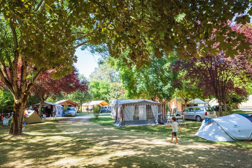 un enfant debout sous un arbre avec des tentes dans l'établissement mobilhome terrasse ombragée 27m2, à Cahuzac-sur-Vère