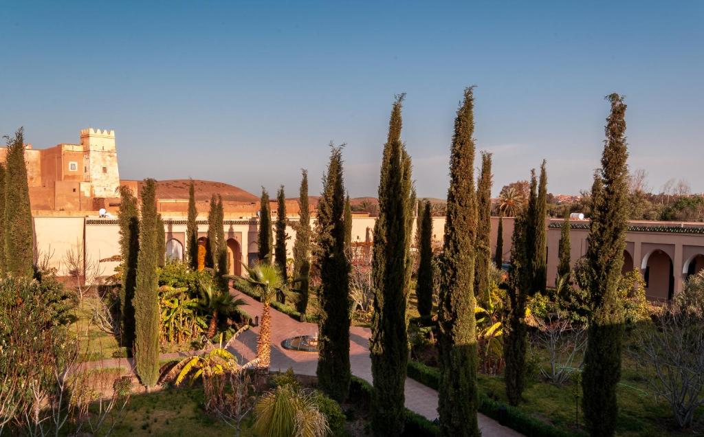 un jardin avec des arbres et un bâtiment en arrière-plan dans l'établissement Riad Sougtani, à Marrakech