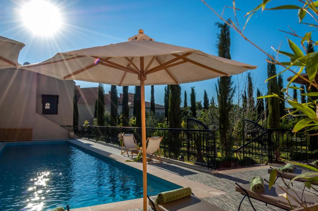 un parasol assis à côté d'une piscine dans l'établissement Riad Sougtani, à Marrakech