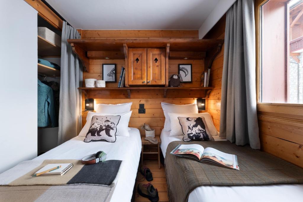 deux lits dans une chambre aux murs en bois dans l'établissement Résidence Pierre & Vacances Premium Les Alpages de Reberty, aux Menuires