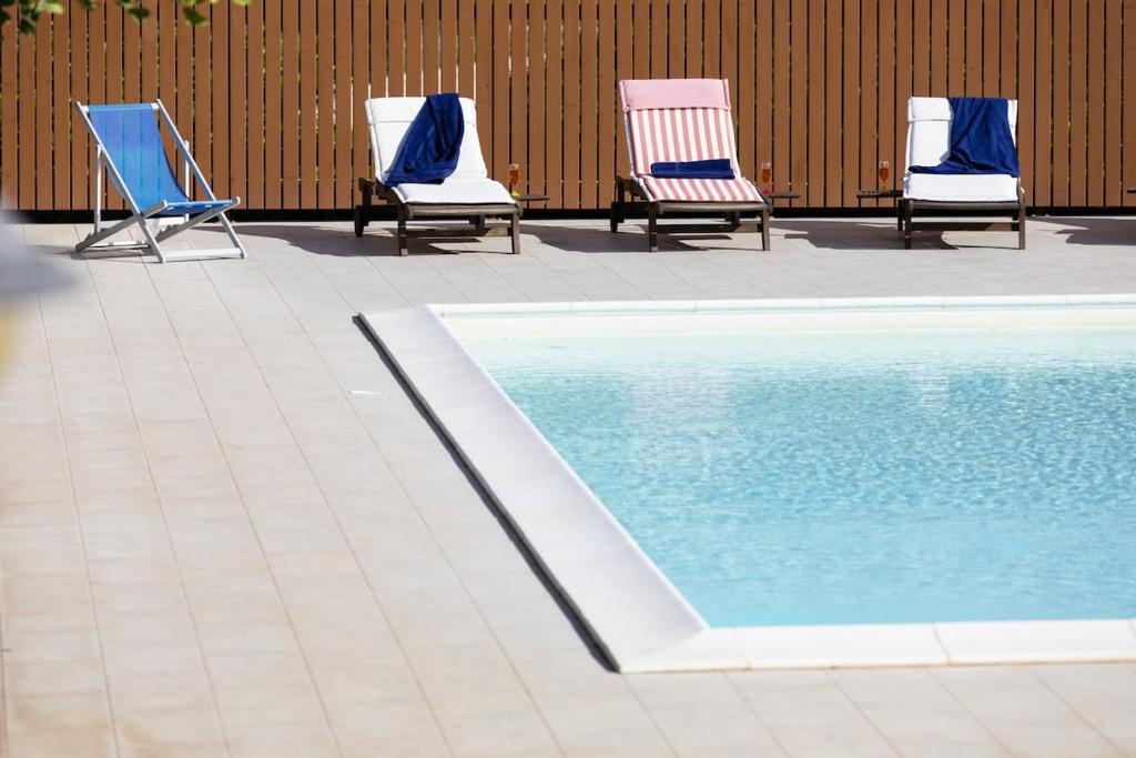 3 chaises et une piscine dans un patio dans l'établissement Casa Natia - IsulaTravel, à Modica
