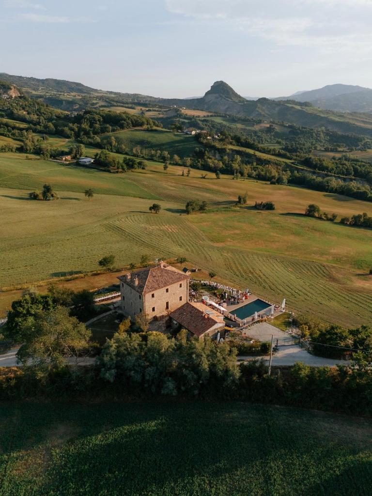 une vue aérienne d'une maison au milieu d'un champ dans l'établissement Palazzo Serre - Natura & Piscina, à San Leo