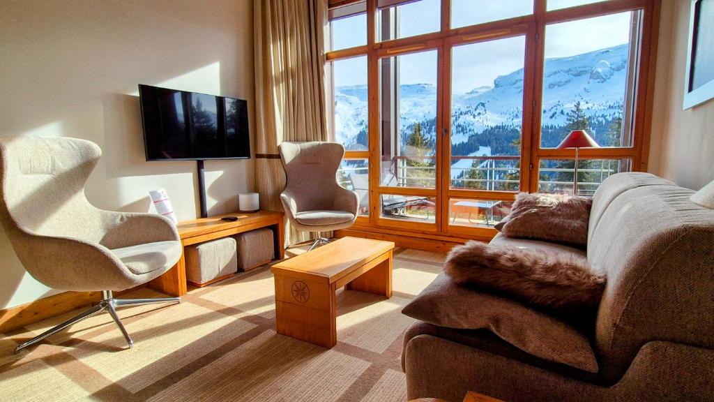 un salon avec un canapé et des chaises et une grande fenêtre dans l'établissement Appartement Premium en pleine nature à Flaine, 8 à 10 personnes - Piscine extérieure chauffée, jacuzzi, sauna, hammam et salle de sport, à Flaine